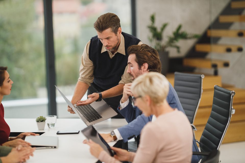 Menschen besprechen gemeinsam Unterlagen am Laptop